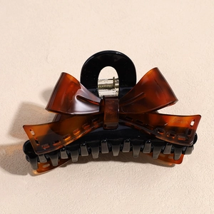Macro view of handmade bow claw clip in tortoise shell finish with engraved logo