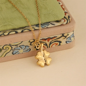 Polished gold stainless steel irregular clover necklace on an embroidered fabric gift box