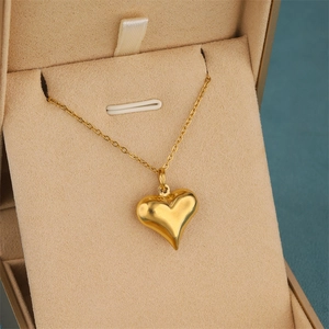 Collier avec pendentif cœur doré poli présenté sur un coussin de boîte à bijoux beige