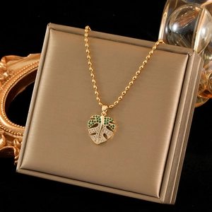 Collier feuille de palmier dorée avec zircons verts et blancs sur un présentoir