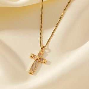 Collier pendentif croix dorée avec détails en cœur et zircons sur fond de soie