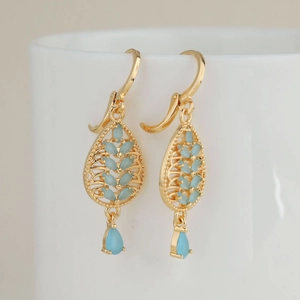 Bohemian 18k gold plated leaf drop earrings with blue cubic zirconia on a white cup