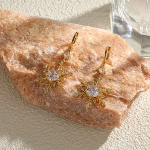 Élégantes boucles d'oreilles flocon dorées avec zircons sertis et détails floraux