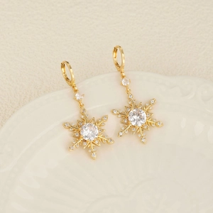Élégantes boucles d'oreilles flocon de neige dorées avec zircone cubique sur une assiette