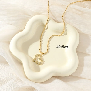 Collana con ciondolo a cuore in oro e zirconi su vassoio in ceramica bianca