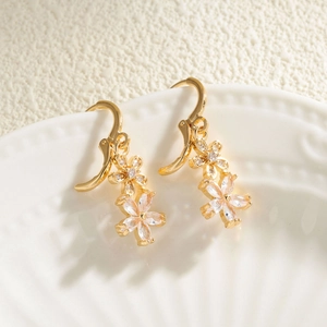 Élégantes boucles d'oreilles fleurs dorées avec cristaux sur une assiette en céramique