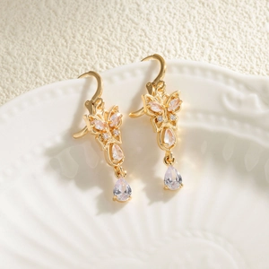 Elegant gold butterfly drop earrings with teardrop zircons on white ceramic plate