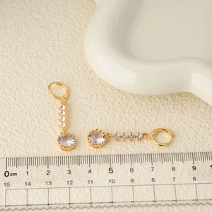 Boucles d'oreilles pendantes dorées avec zircons ronds et sertissage en couronne