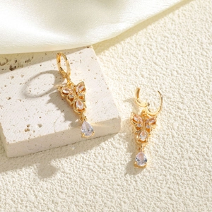Elegant gold butterfly drop earrings with clear zircon waterdrop crystals on stone background