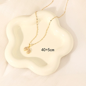 Elegant gold necklace with wheat-shaped zircon pendant on white decorative plate