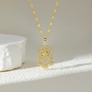 Gold dreamcatcher necklace with snowflake pendant and sparkling star charms on white stone