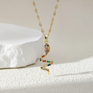 Minimalist gold snake pendant necklace with multi-colored zircons on white stone base