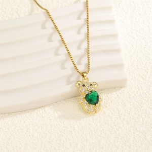 Détail du collier ours doré orné d'une pierre coeur verte et de pierres en zircon blanc