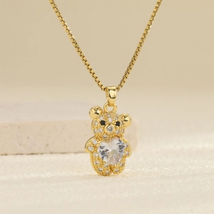 Gros plan du pendentif ours doré avec cœur en zircon étincelant et yeux en pierres noires