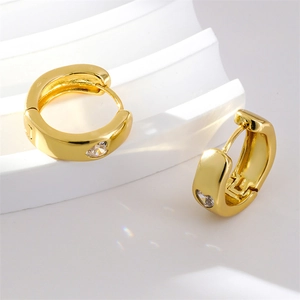 Minimalist gold heart zircon huggie hoop earrings displayed on a geometric stand