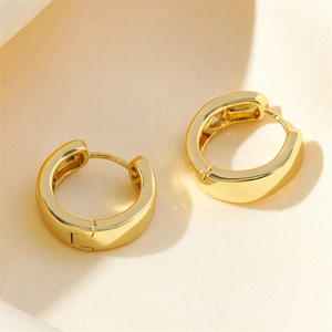 Polished gold geometric heart hoop earrings with zircon inlay on warm fabric background