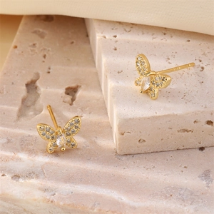 Elegant gold butterfly stud earrings with sparkling cubic zirconia on stone display