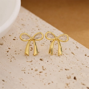 Boucles d'oreilles nœud dorées avec zircone sur un plateau en pierre pour femme