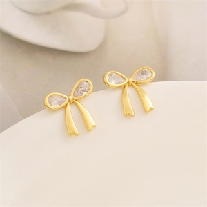Boucles d'oreilles nœud doré avec zircons en goutte sur bordure en céramique blanche