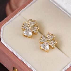 Golden four-leaf clover stud earrings with pavé zircon displayed in a pink gift box