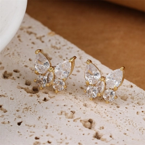 Elegant gold butterfly stud earrings with sparkling crystals on a textured stone base