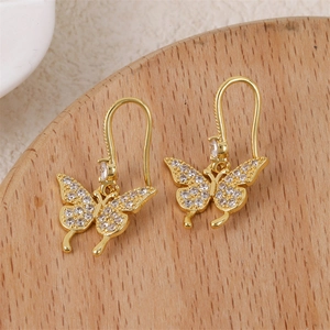 Eleganti orecchini a farfalla in oro 18K con pietre di zircone su uno sfondo di legno