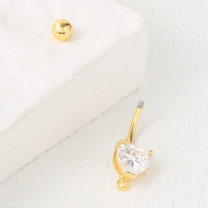 Piercing de nombril en or poli avec un zircon en forme de cœur sur fond de pierre blanche