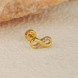 Détail macro d'un piercing d'oreille infini doré avec zircons micro-incrustés