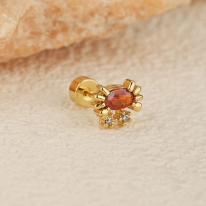 Détail macro d'une boucle d'oreille crabe dorée avec pierre orange et fermoir à vis