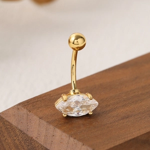 Gold stainless steel navel ring with marquise-cut zircon on dark wooden base