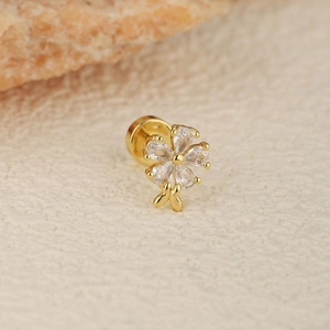 Macro shot of gold flower labret stud with crystal petals and tiny bow on leather