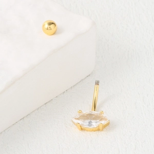 Golden belly button piercing with marquise cut zircon gemstone on white stone display