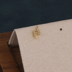 Vue macro de boucles d'oreilles éclair dorées avec zircons étincelants pour femme