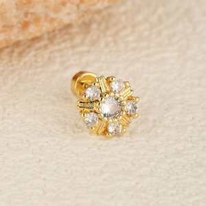 Macro detail of a golden flower cartilage stud earring with cubic zirconia center stones