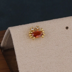 Détail macro d'une boucle d'oreille crabe en or avec pierre orange et zircons brillants