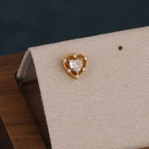 Macro shot of gold heart cartilage piercing with clear zirconia cluster setting details