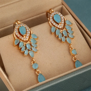 Detail von goldenen Hängeohrringen mit blauen Zirkonia-Wassertropfen und Quastenketten