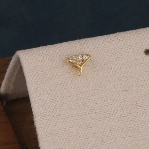 Vue macro d'une boucle d'oreille dorée en forme d'éventail avec cinq pierres blanches