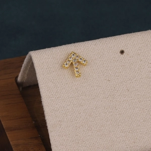 Macro shot of gold-plated arrow cartilage stud earring with cubic zirconia inlay