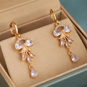 Makroansicht von Gold-Ohrringen mit Zirkonia-Blumencluntern in einer beigen Schmuckbox