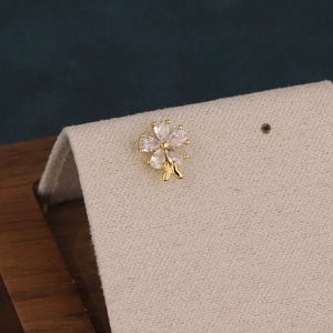 Macro detail of flower cartilage piercing with zircon petals and gold butterfly charm