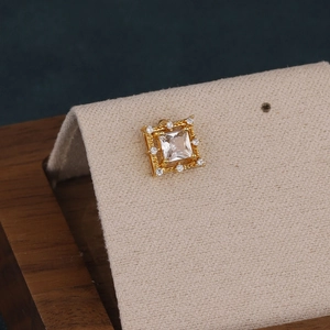 Macro shot of gold square stud earring with large clear zircon and micro-pavé details