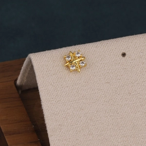 Macro view of a gold-plated cross star cartilage earring with sparkling zircon stones