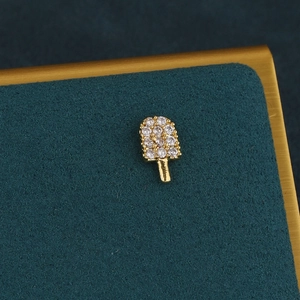 Vue macro d'une boucle d'oreille glace dorée avec zircons sur velours vert foncé