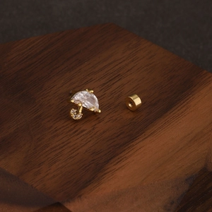 Macro detail of gold umbrella earring with teardrop zircon and screw ball back