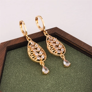 Elegante goldene Tropfenohrringe mit Zirkon-Blattdesign auf dunklem Holztablett