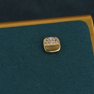 Détail d'un piercing d'oreille éclair doré serti de cristaux brillants sur fond vert