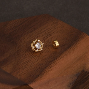 Detail of flower-shaped stud earring with zircon stone on walnut wood display stand