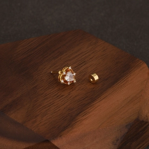Macro shot of gold heart cartilage earring with sparkling cz stones on dark wood