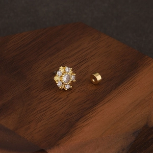 Detailed macro view of gold sunflower cartilage stud with sparkling cubic zirconia stones